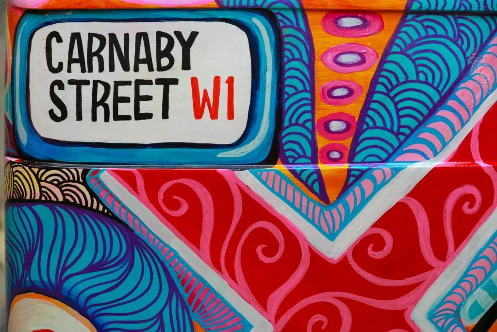 Colourful wall art with the street sign for Carnaby Street in the corner
