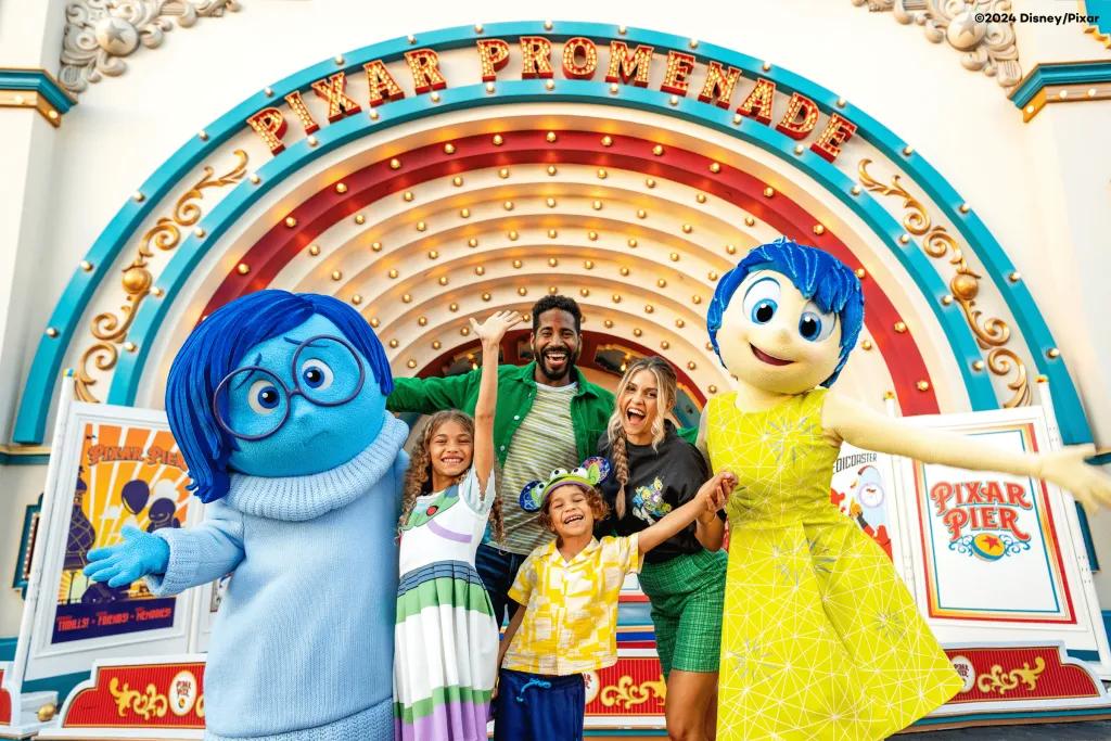 A family posing with Joy and Sadness from Inside Out at Pixar Pier
