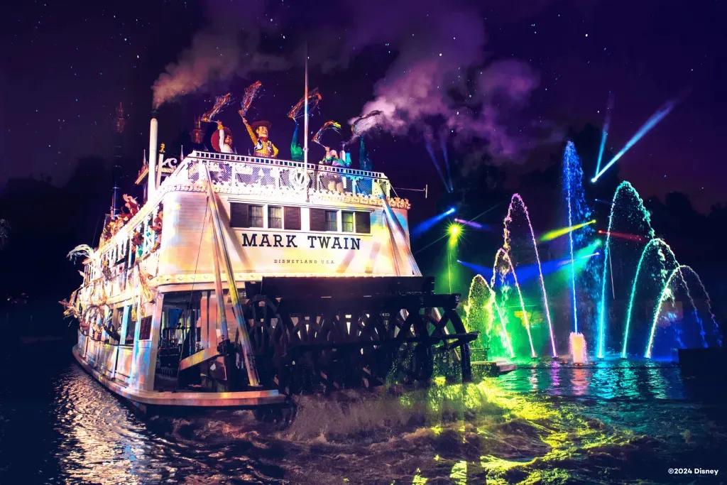  Beliebte Disney Figuren sind auf einem altmodischen Flussschiff mit hell erleuchteten Wasserspielen im Hintergrund unterwegs