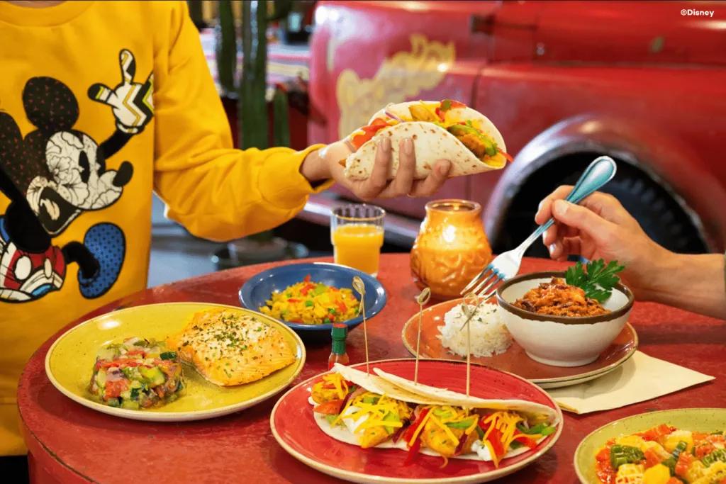 Two people reaching over a table covered in plates of Tex Mex food