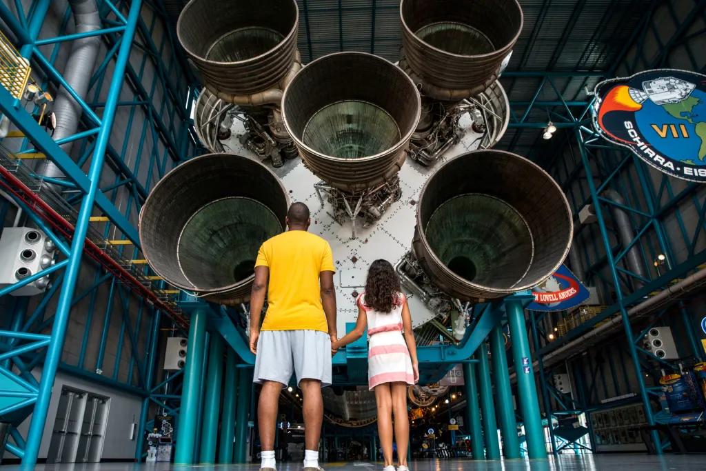 Father and daughter looking up at the Saturn V Rocket at Kennedy Space Center