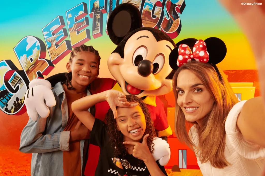 A mum taking a selfie with her two children posing with Mickey Mouse in the background