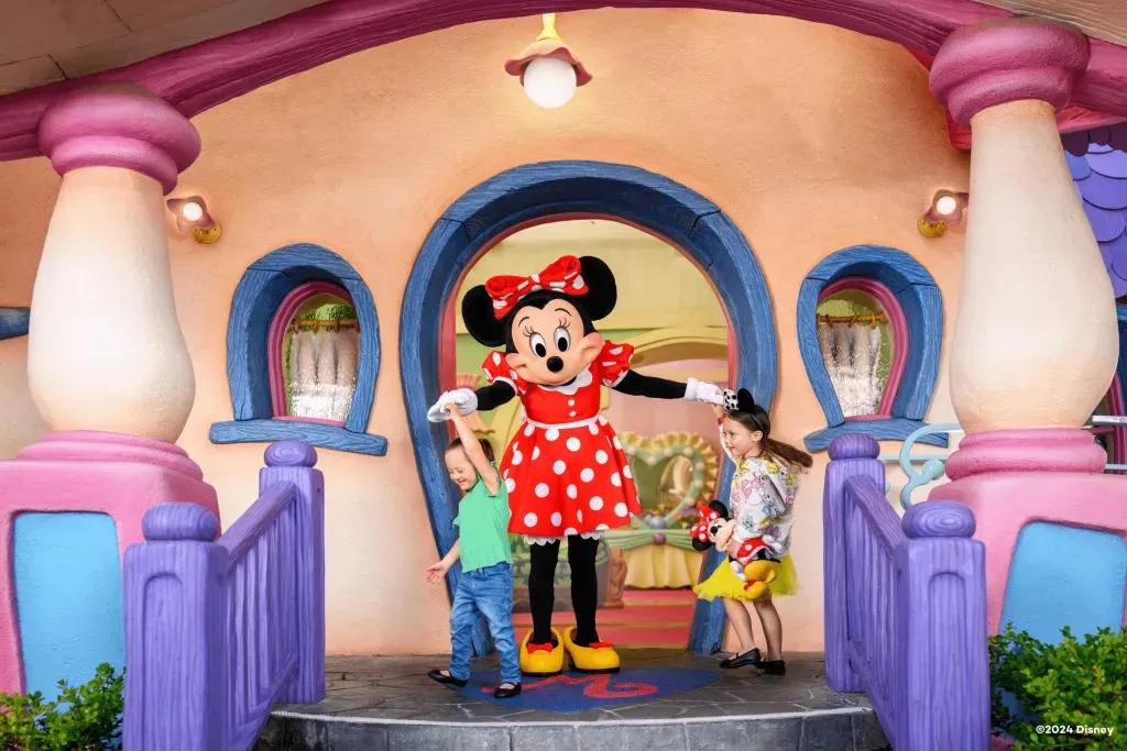 Zwei kleine Mädchen tanzen mit Minnie  auf den Stufen ihres Hauses in Disneyland   