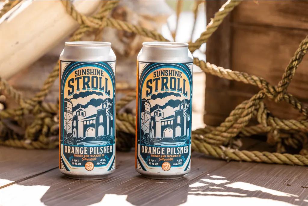 Two cans of Sunshine Stroll pilsner on a decking with rope in the background