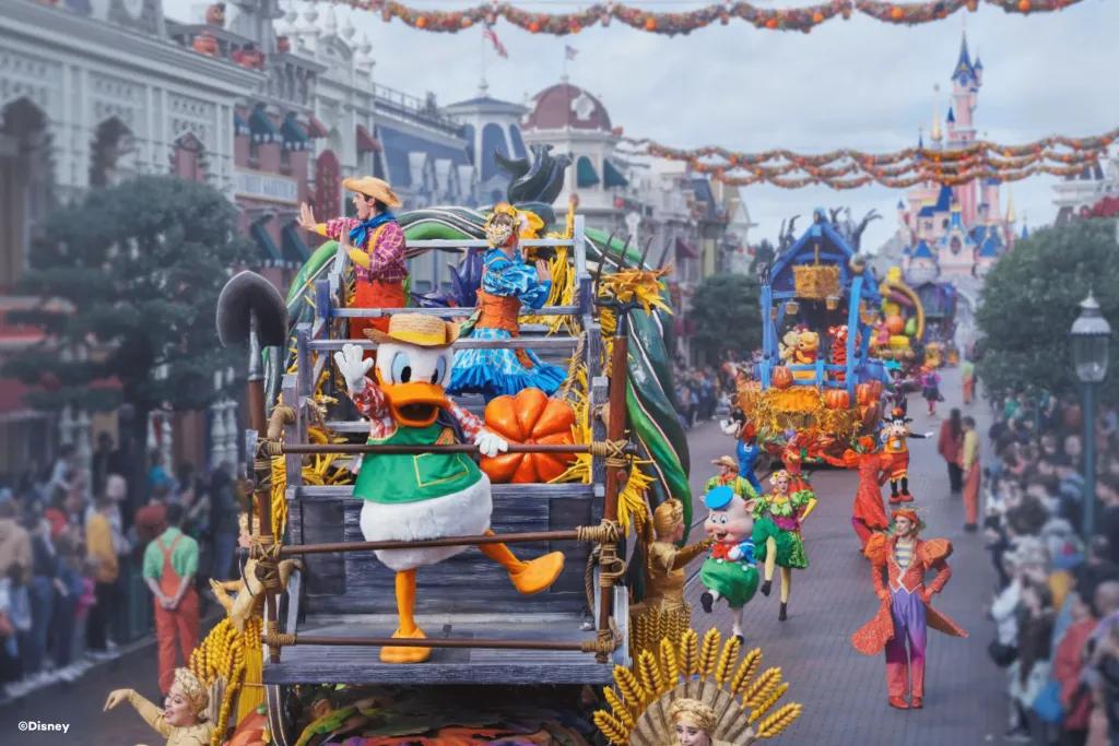 Donald Duck in a farmer costume leading a parade of floats coming down Main Street USA