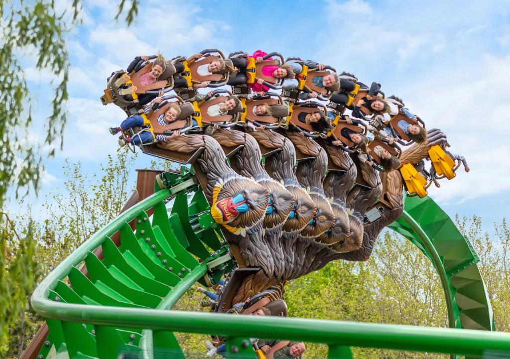 A winged rollercoaster designed to look like a mandrill holding people as they ride