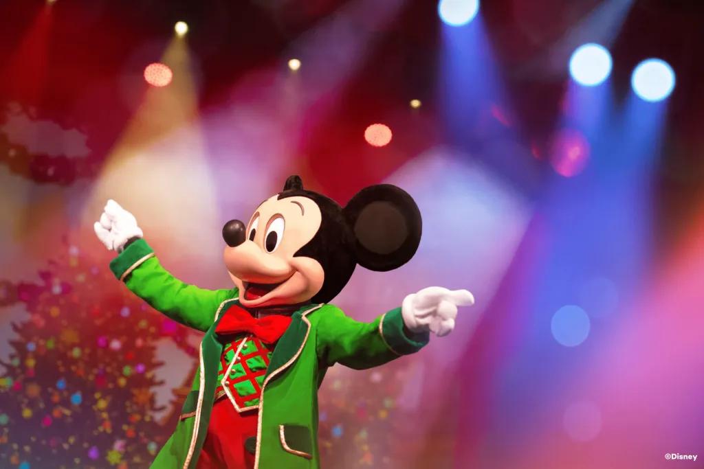 Mickey Mouse in a festive outfit holding out his hands as if conducting an orchestra
