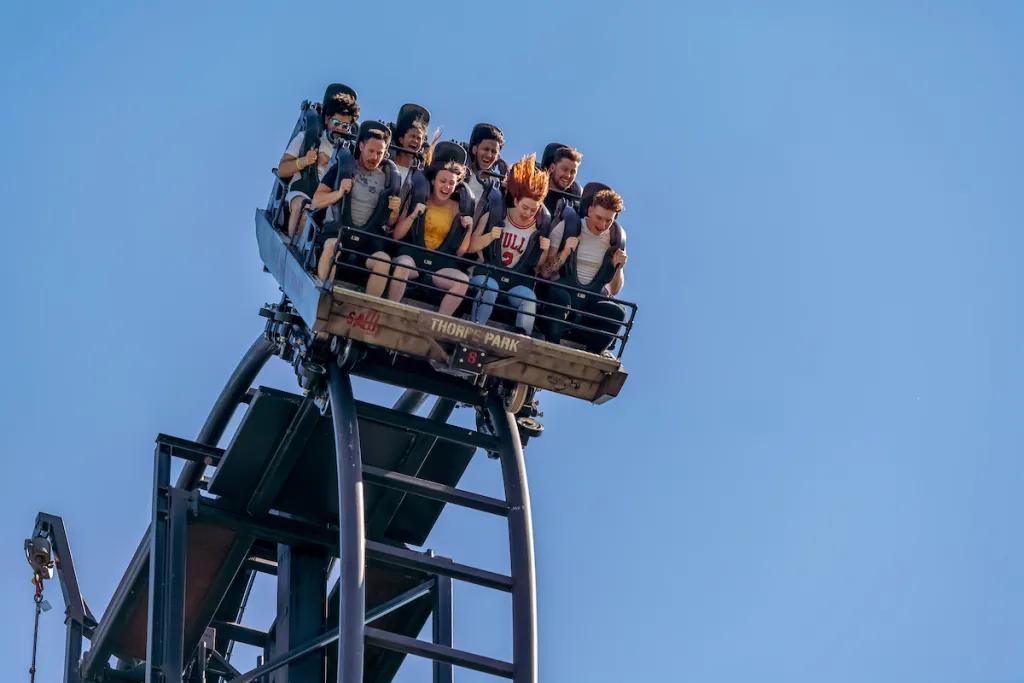 People in a ride car at the top of a rollercoaster drop