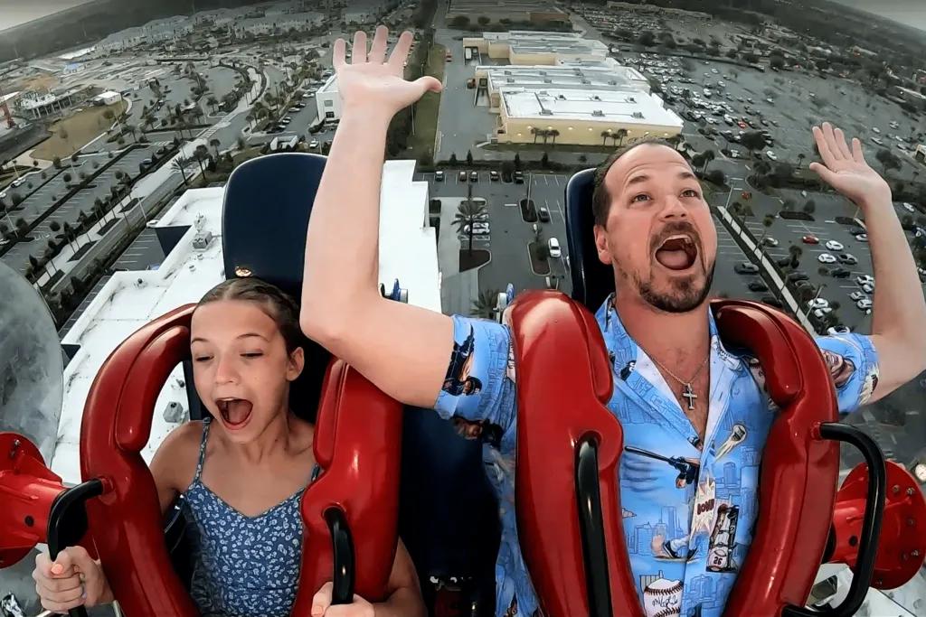 A man and young girl screaming on a slingshot ride