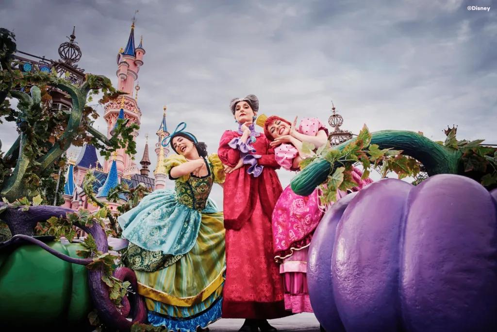 Cinderella's stepsisters and stepmother posing behind large pumpkins in front of Sleeping Beauty Castle