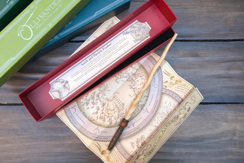 A Harry Potter wand on top of a map next to a pile of colourful wand boxes