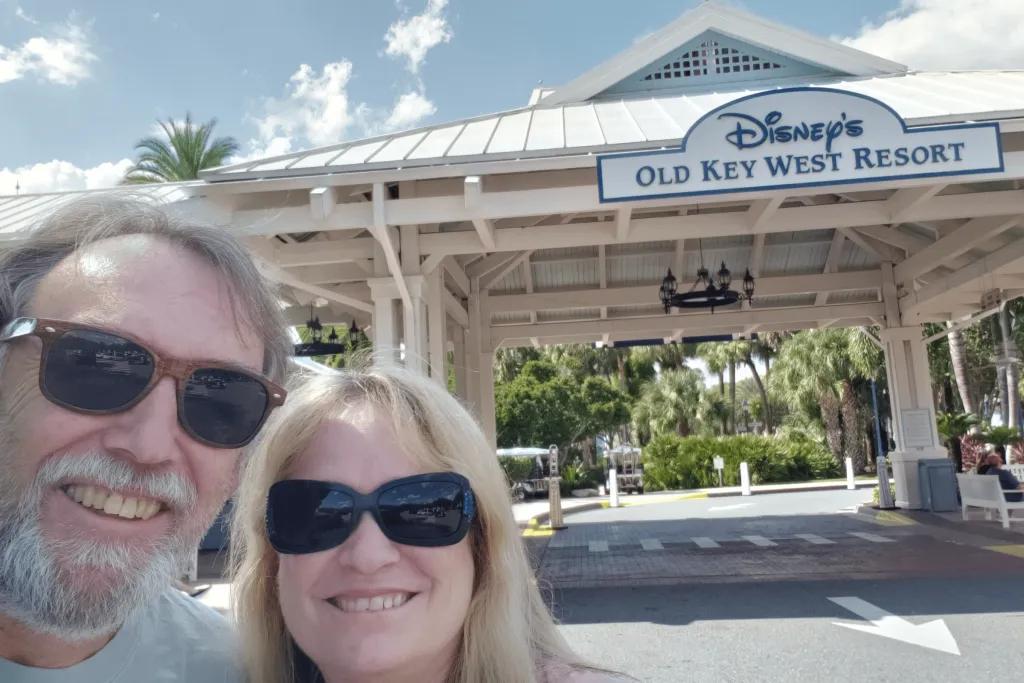 Man and woman taking a selfie in the road with a small wooden roof over it and a sign saying "Disney's Old Key West Resort"