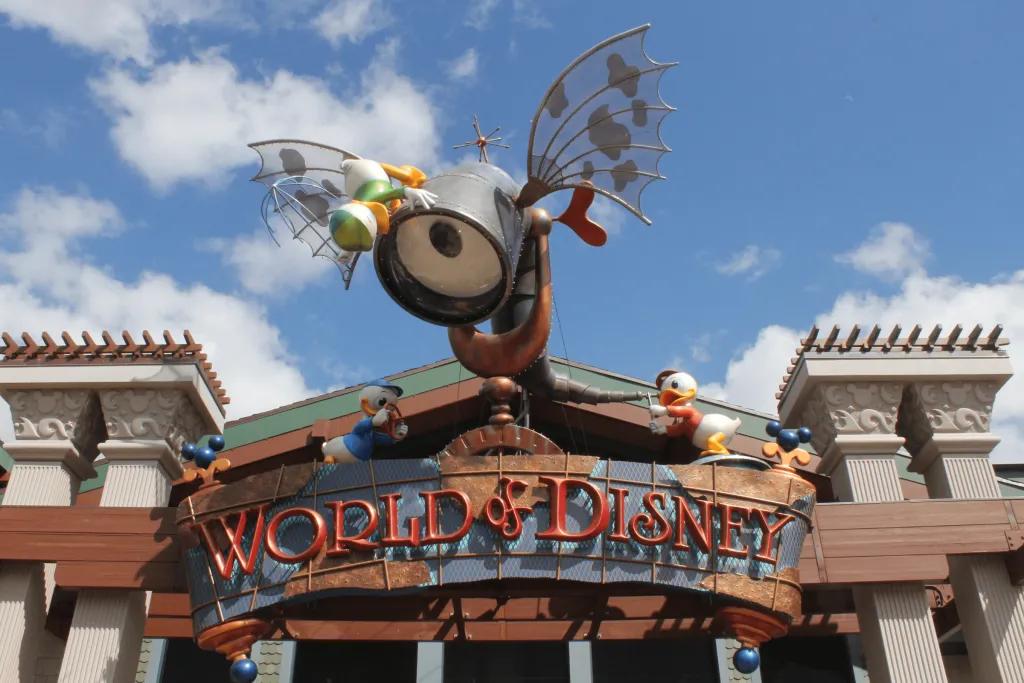There is a large shop with a huge wooden sign saying World of Disney in red. There is a cartoon sculpture of an eye looking through a telescope.