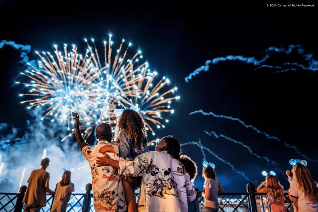 Family of three, with two parents holding up their little girl to see the fireworks in the sky better.