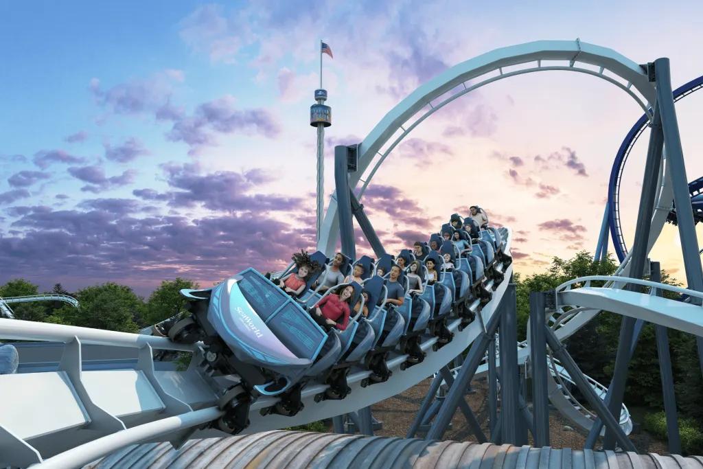 Art of a family coaster which is icy blue and has many people sat smiling on it as it curves around bends. In the background the sun is setting pink and blue hues.