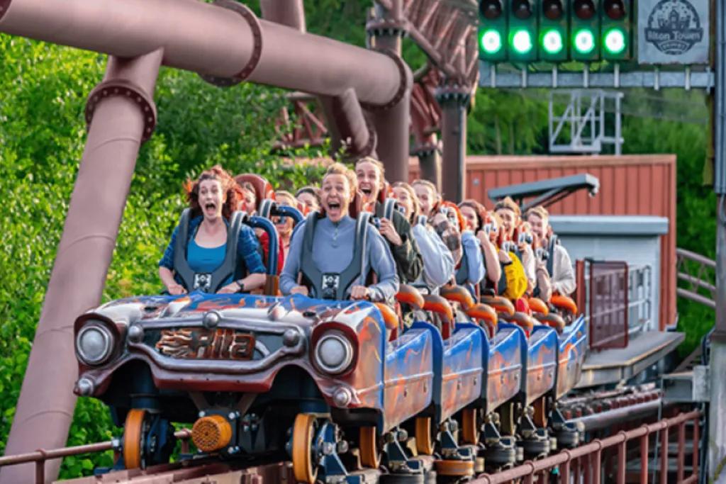 Rollercoaster shaped like a car speeding down launch with traffic light's lit green above.