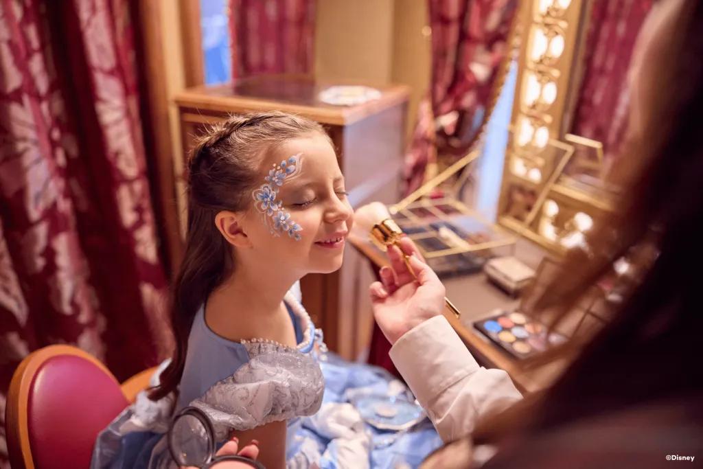 A young girl dressed as Cinderella getting her face painted