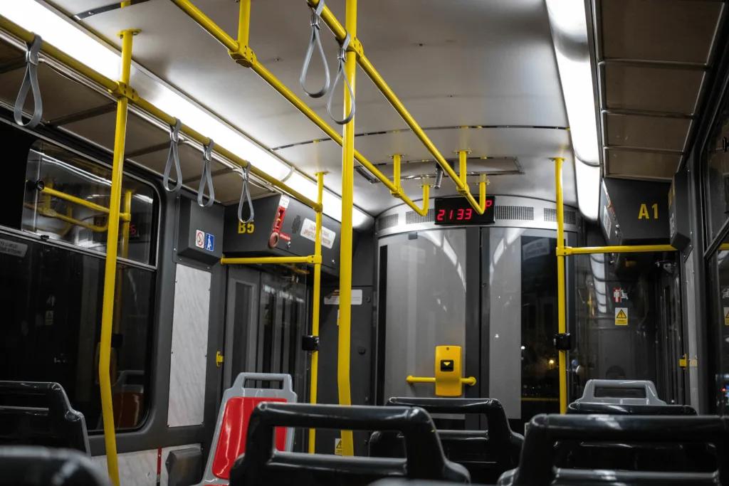 There is a grey bus with yellow poles to hold on to. 