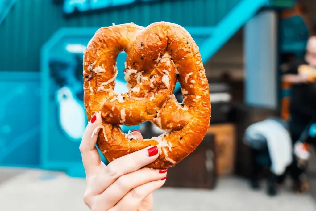 Hand holding up a SeaWorld Pretzel in front of a blue building