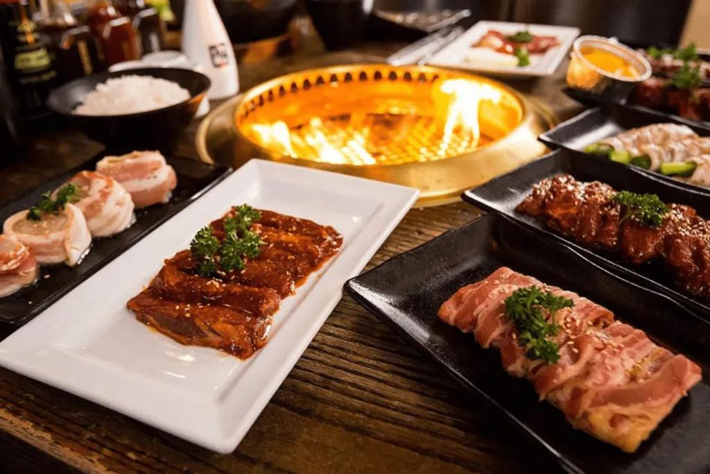 Small firepit in centre of table with plates of food surrounding it.