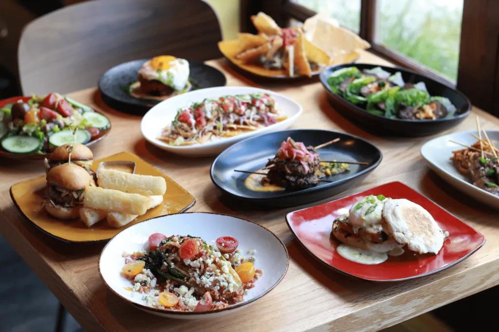 Lots of plates of different dishes from different cuisines including small burgers and other dishes.