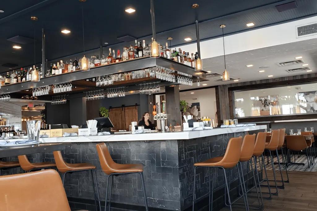 A dark grey bar with brown leather bar stools in a modern restaurant and bar.