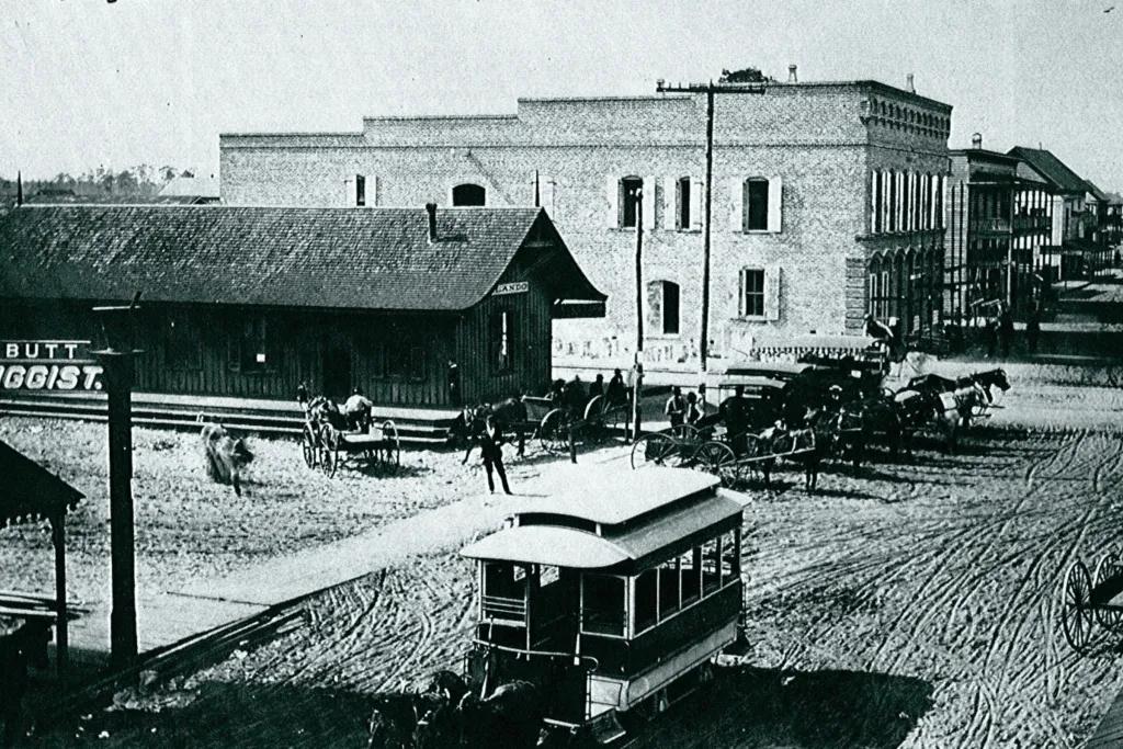 Old street with dirt tracks and horses pulling carriages along.