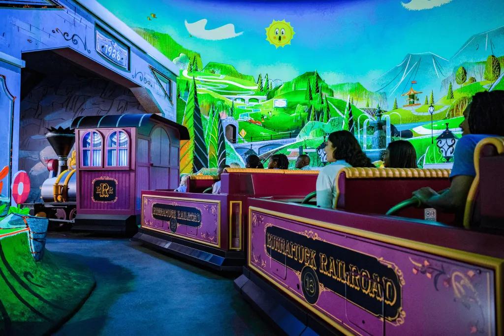 A train shaped ride with rows of four going through a cartoon world.