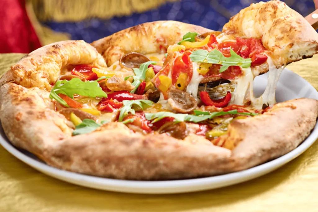 Vegetarian deep dish pizza full of vegetables including peppers, olives and artichokes. 