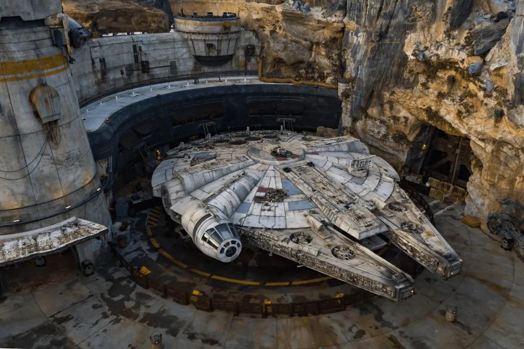 Millenium Falcon (a grey flat shaped space ship) parked on batuu, a mythical stone filled island.