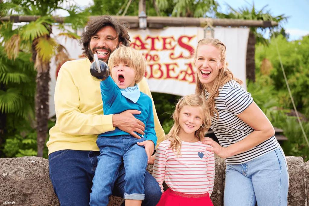 A family of two parents and two kids posing in front of Pirates of the Caribbean