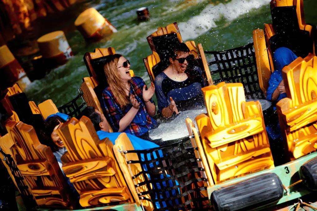 People screaming as they're getting splashed on a river rapid ride
