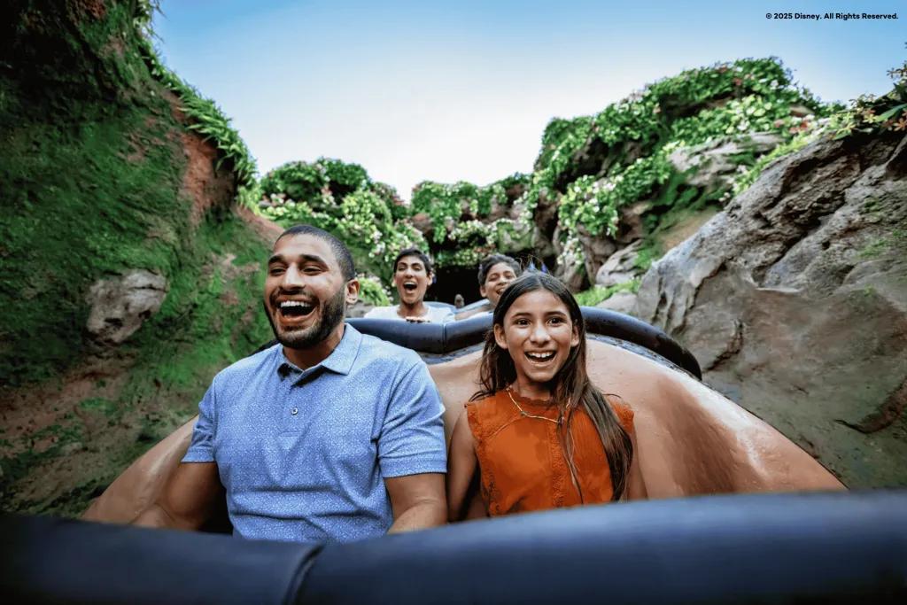 A man and young girl smiling while going down the drop on a log flume