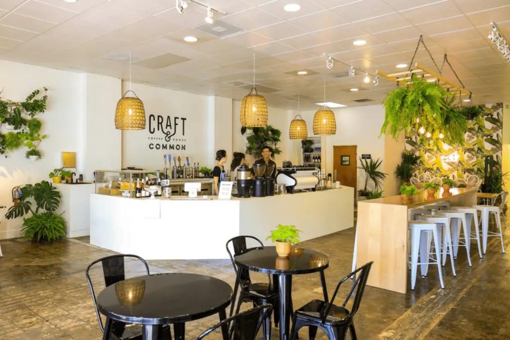 Open air, light white coffee shop decorated with plants.