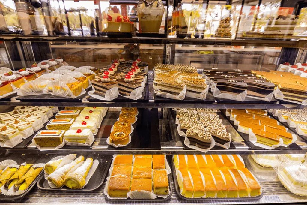 A selection of different pastries and cakes behind a glass case in a cafe.
