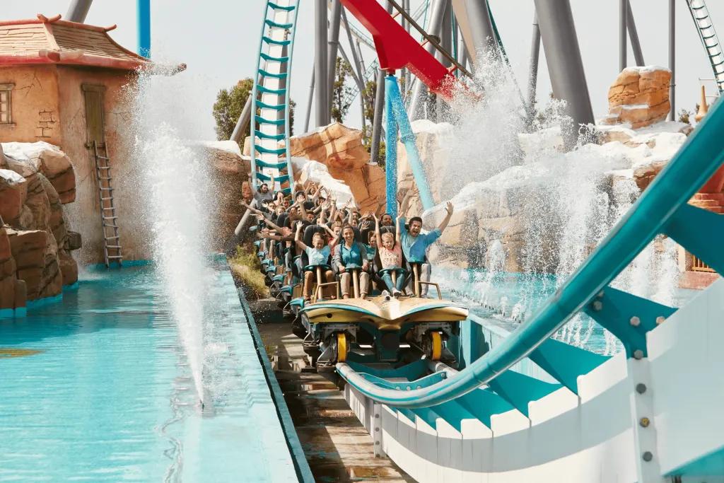 A rollercoaster car coming down a drop into a splash of water
