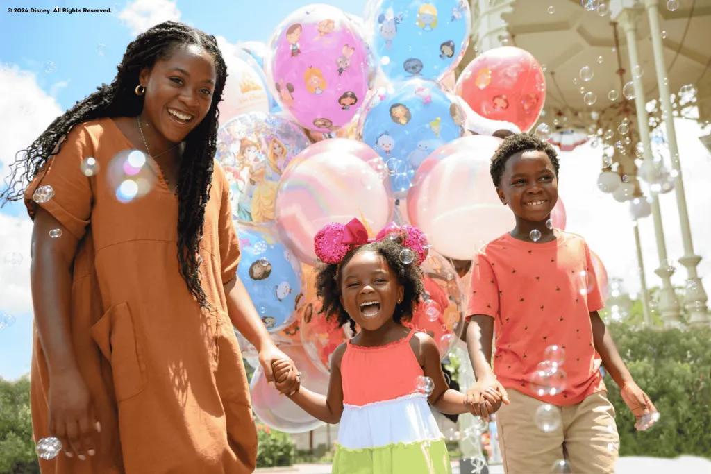 A mum with her young son and daughter in front of Disney themed balloons