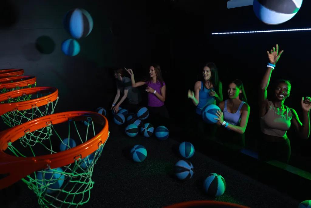 Group of adults playing a basketball game in a dark room.