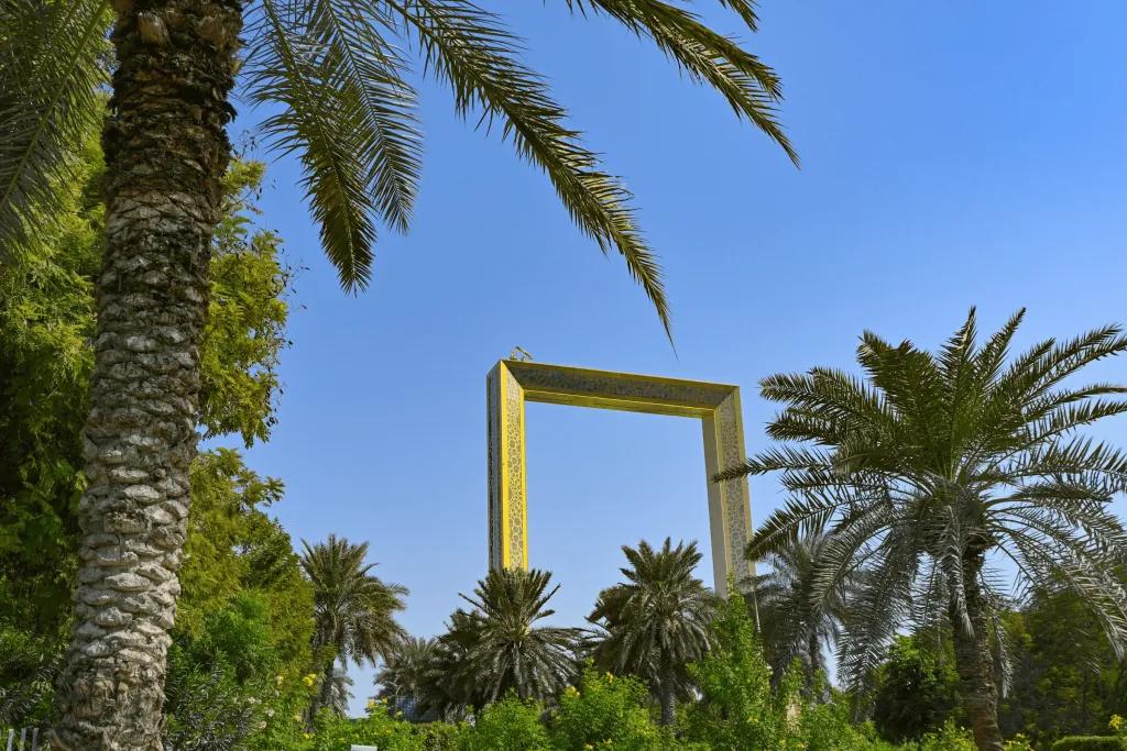 A tall golden building shaped like a picture frame which huge whole in the middle. At the top there is a viewpoint.
