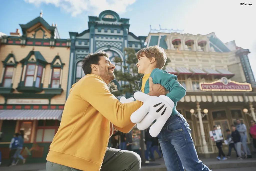  Ein Vater und sein kleiner Sohn umarmen sich, während sie auf der Main Street USA stehen