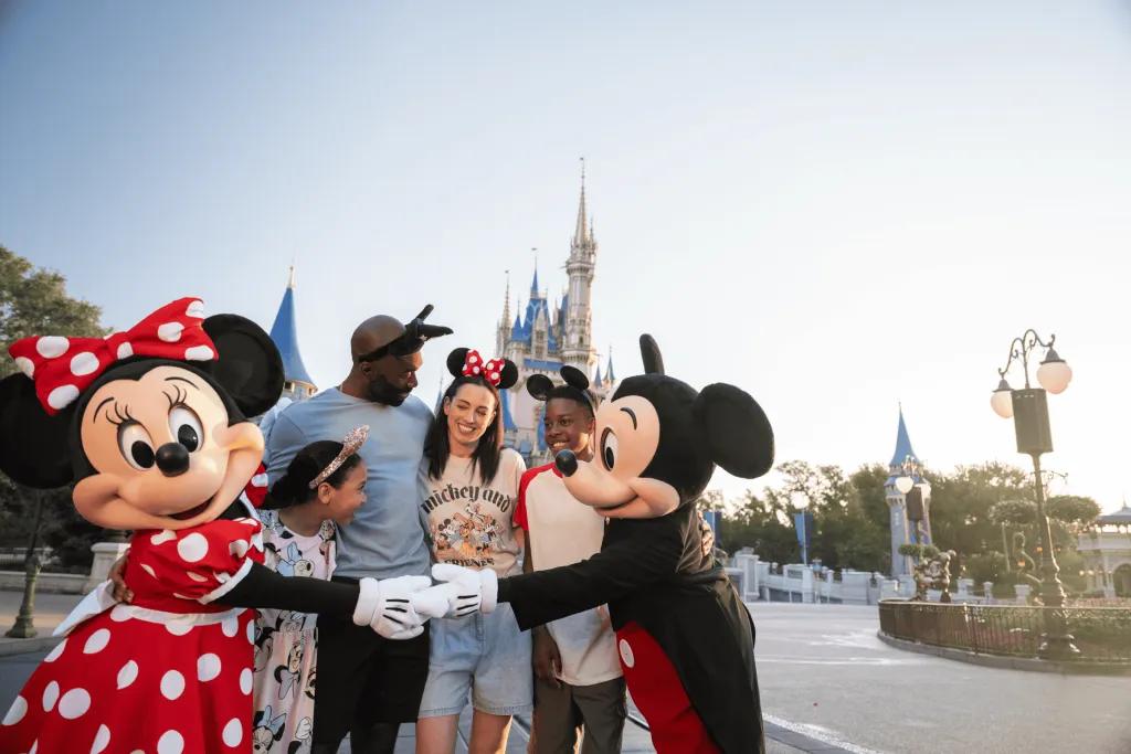 A family hugging Mickey and Minnie Mouse in front of Cinderella Castle