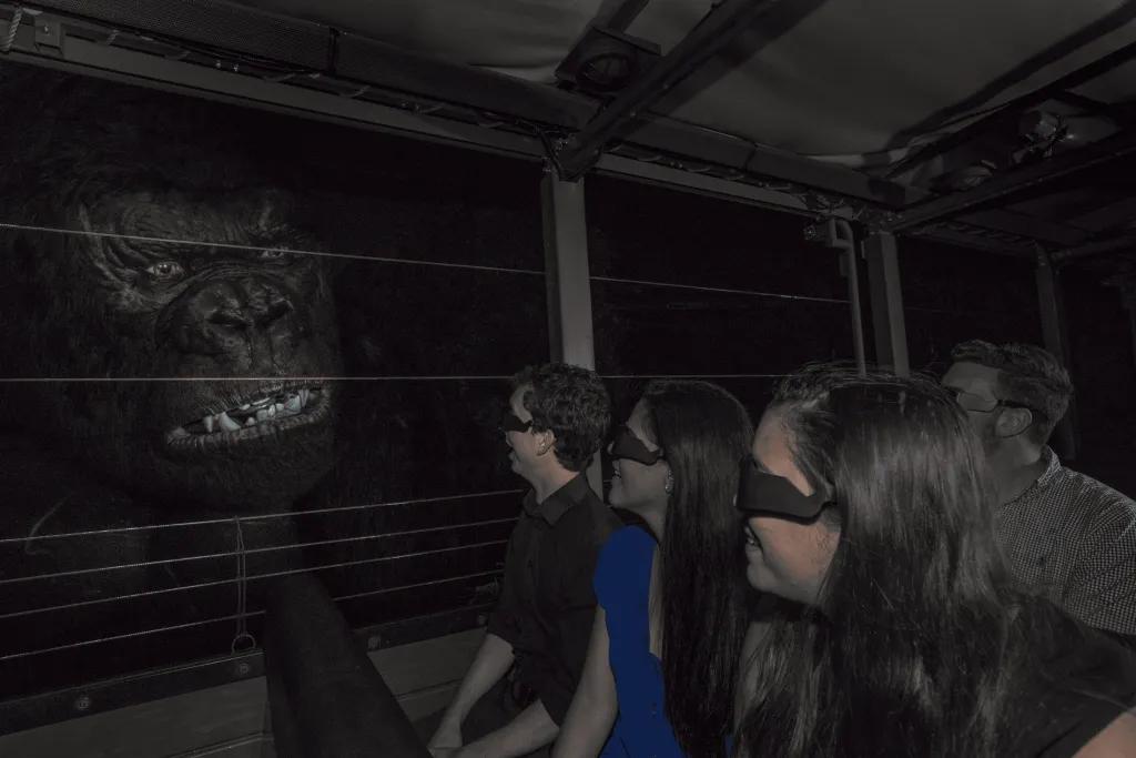 People wearing 3D glasses on a ride vehicle facing towards a giant animatronic gorilla