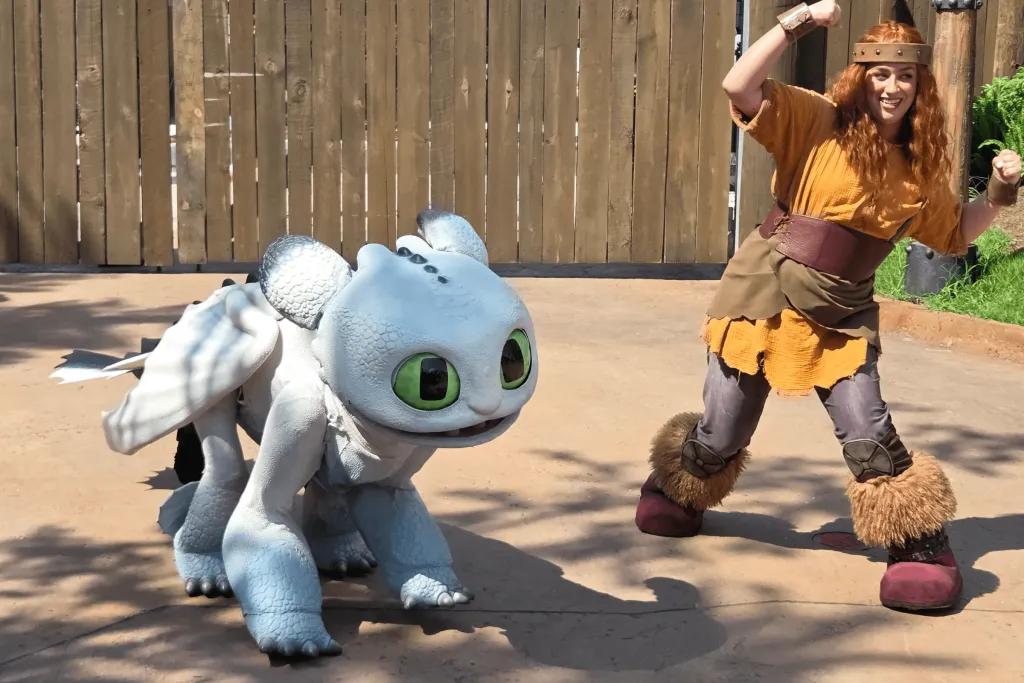 Baby white dragon stood with its viking trainer.