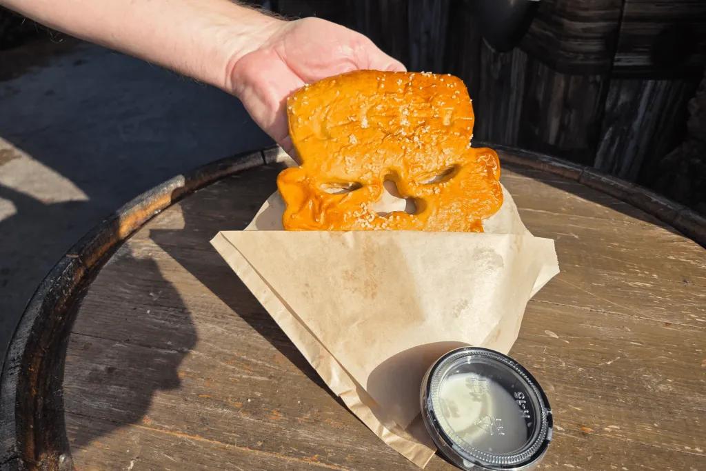 Frankenstein head shaped soft pretzel with pot of sauce.