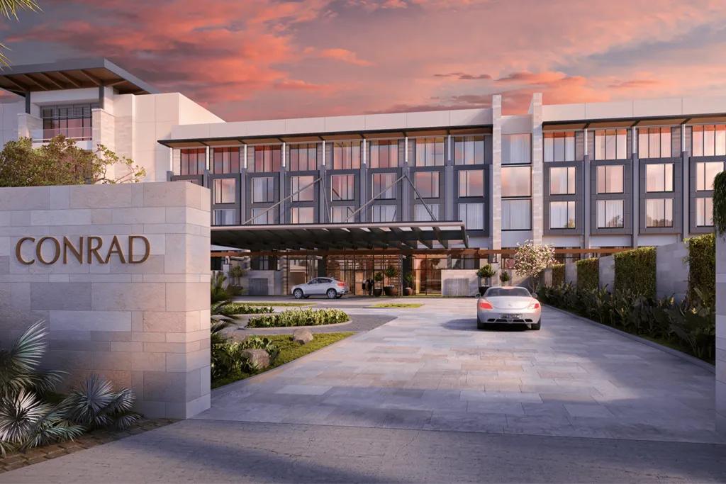 A sleek modern white building/ hotel with a large sign outside saying "CONRAD".