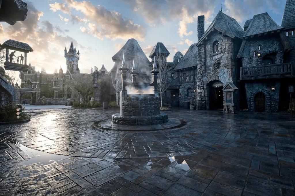 Dark village with grey buildings and rain on the floor and a fountain in the centre of the square.