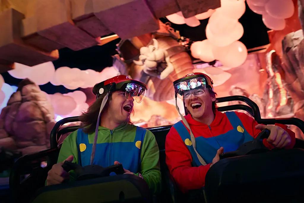 Two people dressed as Mario and Luigi on a Mario Kart attraction