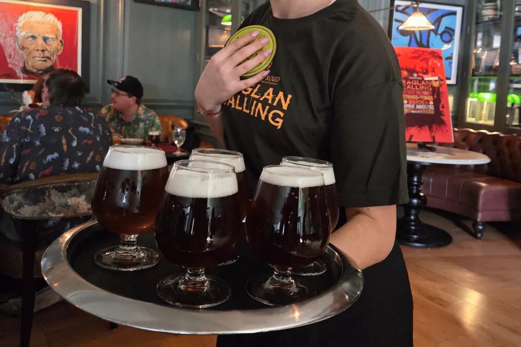 Woman holding a tray of 5 beers wearing a Raglan Road t-shirt.