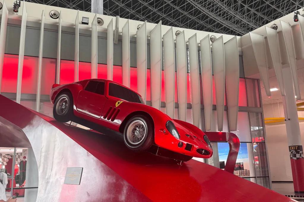 A Ferrari model displayed on a red slope curving up towards the gift shop.