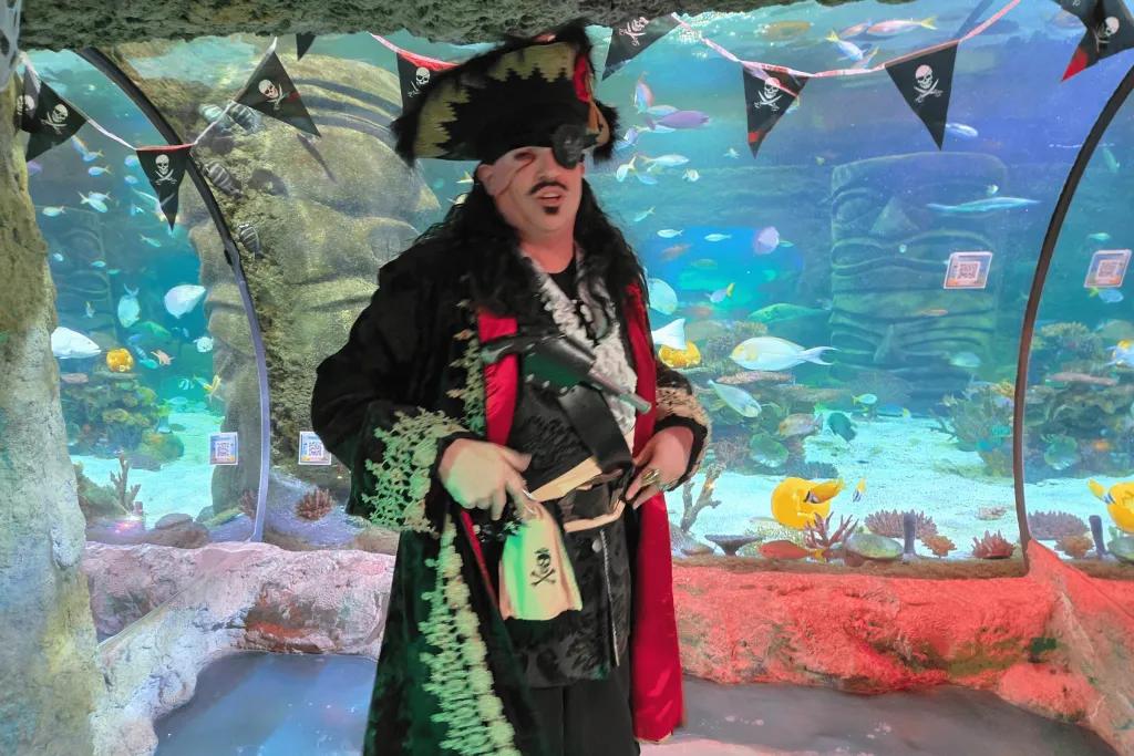 Man dressed as pirate in front of the aquarium glass view points.